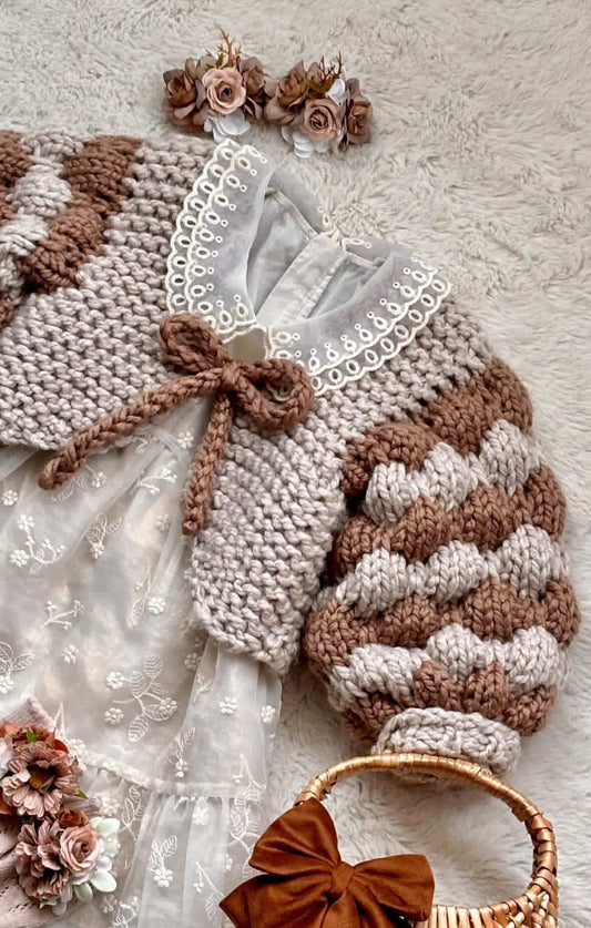 Baby wearing a handknitted bubble sleeve bolero cardigan in super chunky chenille yarn