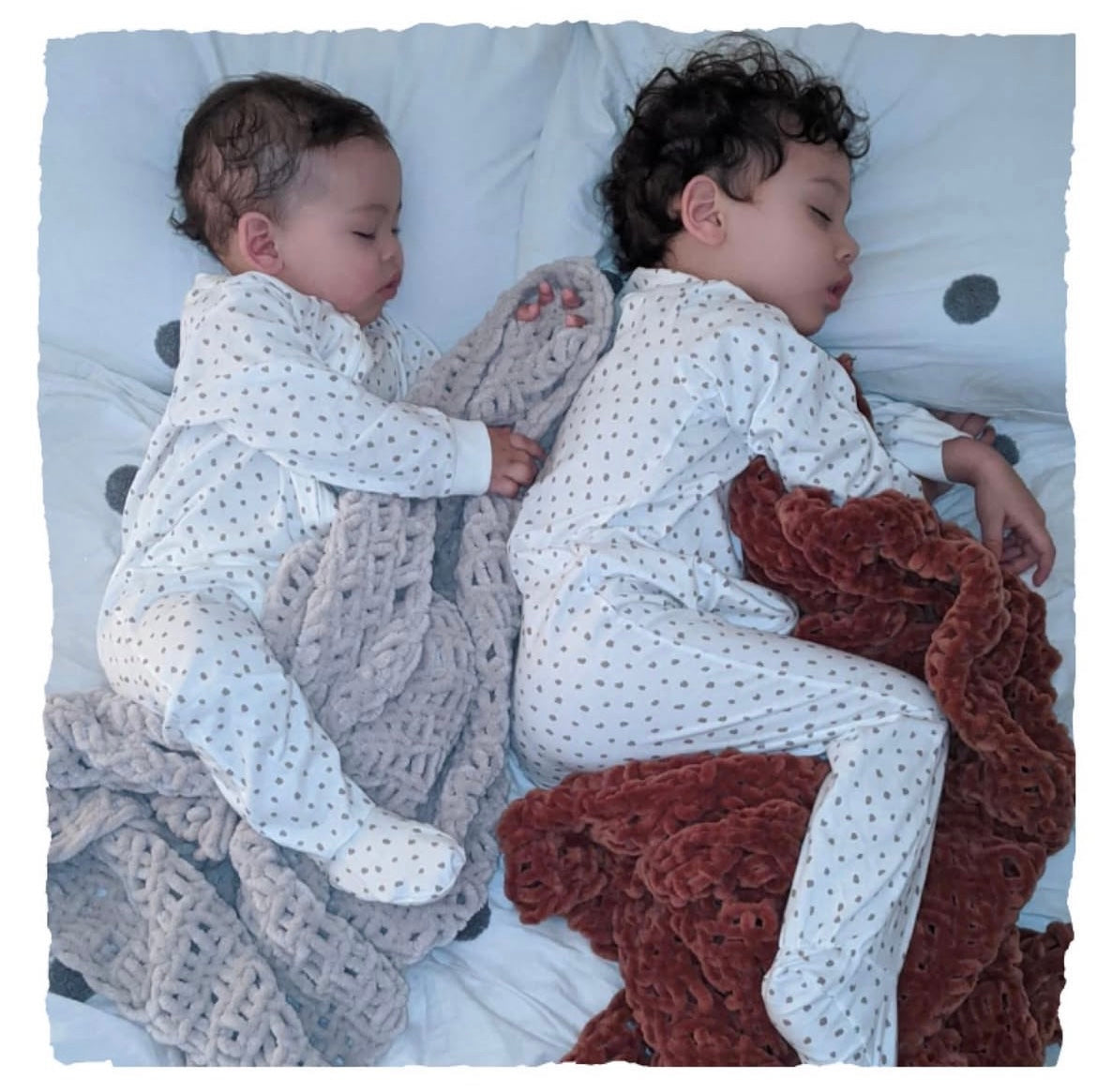 Two children in matching outfits sleeping with hand-knitted chenille blankets