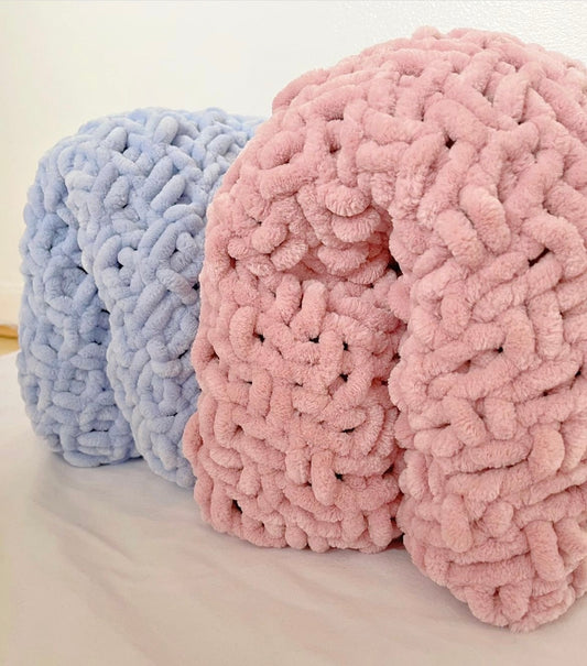 Two hand-knitted chenille toddler blankets in dusky pink and blue, rolled and displayed side by side, showcasing thick, ultra-soft texture—perfect for cosy toddler bedding or nursery decor.