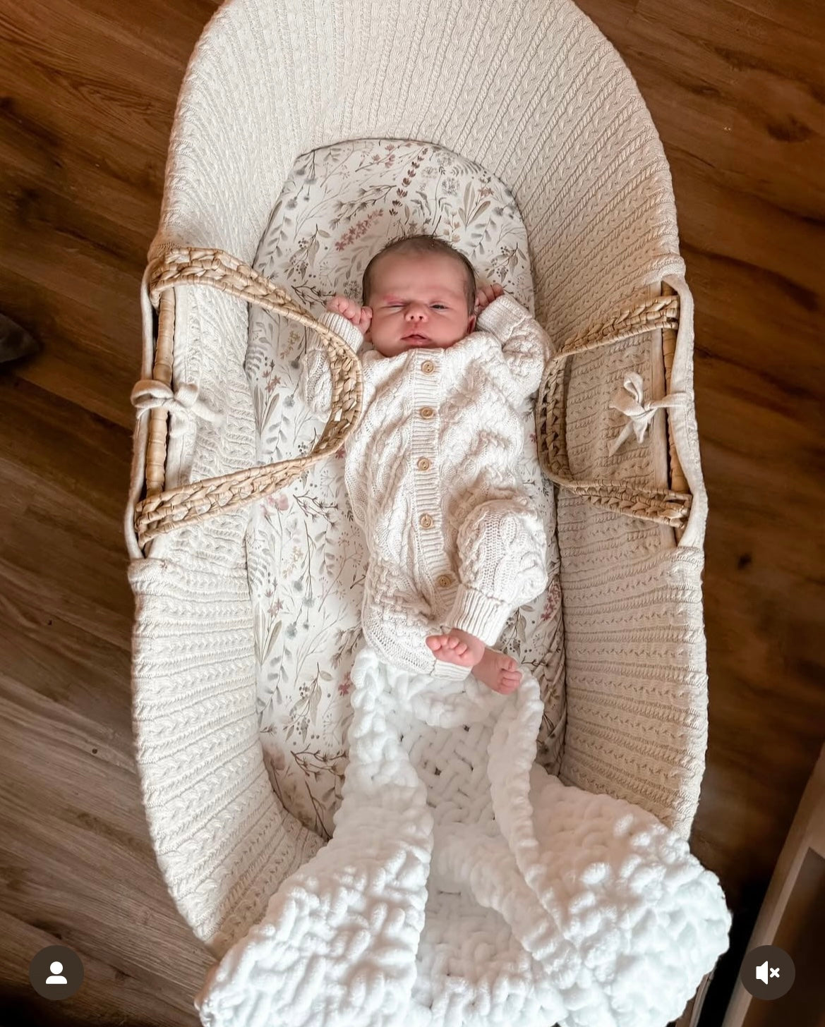 Newborn baby in a Moses basket with a white knitted chenille baby blanket